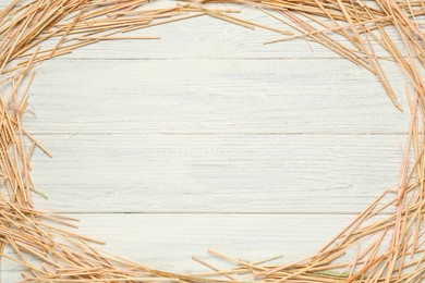 Photo of Frame made of dried hay on white wooden background, top view. Space for text