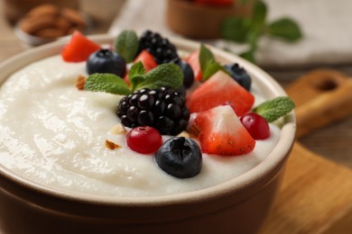 Photo of Delicious semolina pudding with berries in bowl on table, closeup