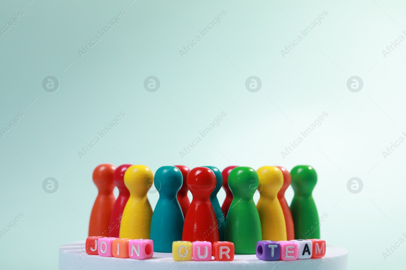 Photo of Colorful cubes with phrase Join Our Team and pawns against light blue background, closeup with space for text. Recruiter searching employee