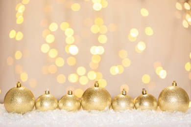 Photo of Beautiful shiny Christmas balls on snow against blurred festive lights, space for text