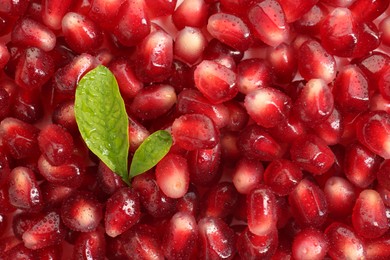 Photo of Green leaves on ripe juicy pomegranate grains, top view