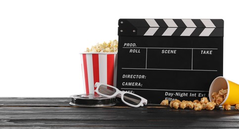 Photo of Movie clapper, buckets of tasty popcorn, glasses and film reel on wooden table against white background, space for text