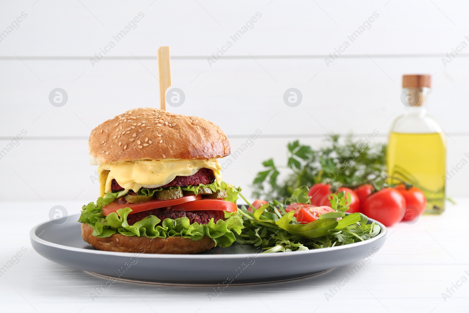 Photo of Delicious vegetarian burger served with salad on white wooden table