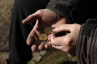 Photo of Poor homeless man holding coins outdoors, closeup