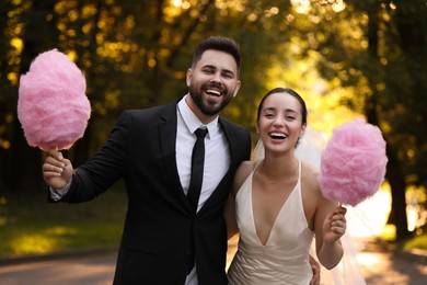 Photo of Happy newlywed couple with cotton candies in park