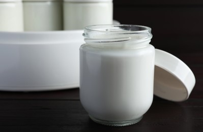 Photo of Glass jar with tasty yogurt on wooden table, closeup
