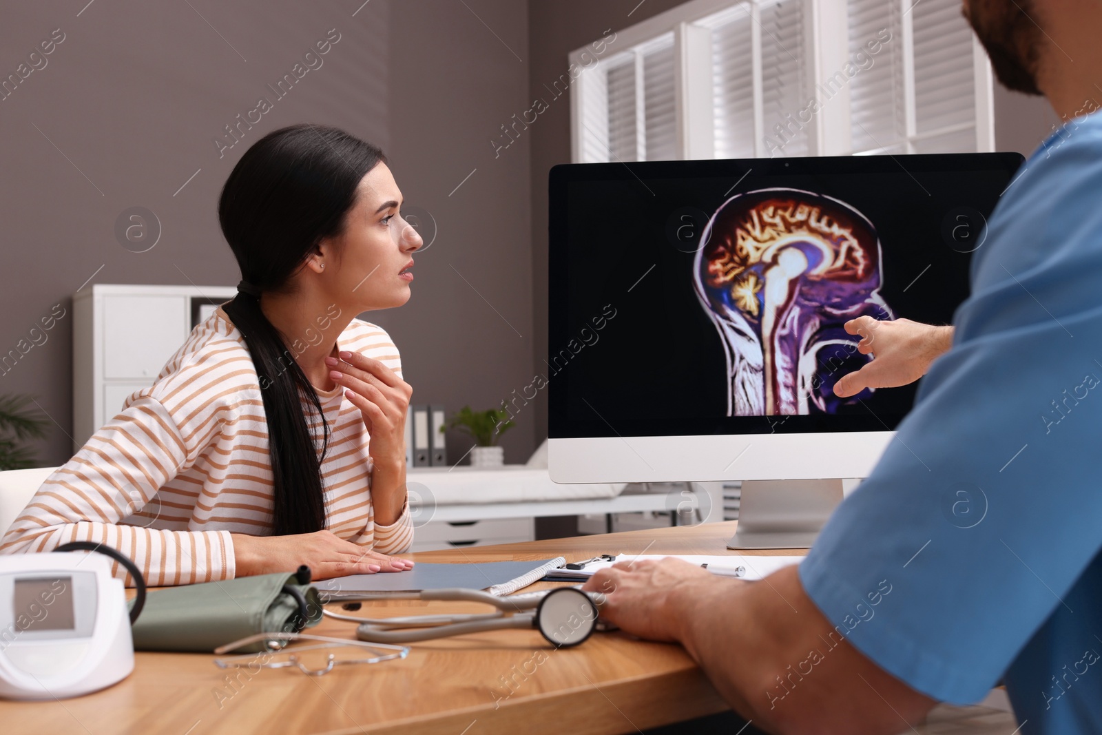 Photo of Neurologist showing brain scan to young woman in clinic