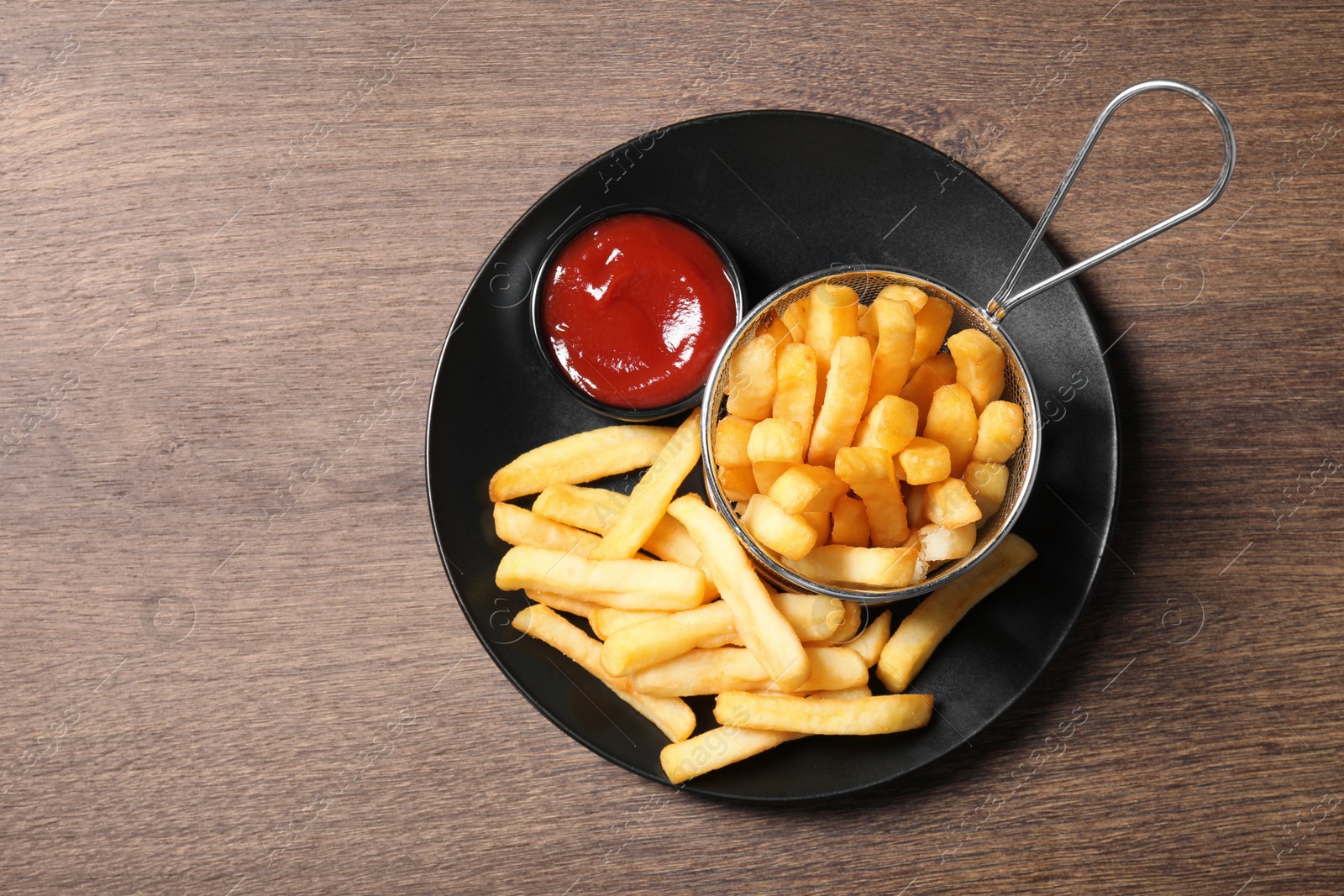Photo of Delicious French fries served with ketchup on wooden table, top view. Space for text