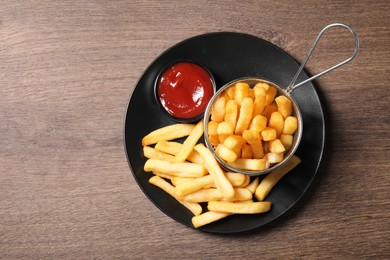 Delicious French fries served with ketchup on wooden table, top view. Space for text