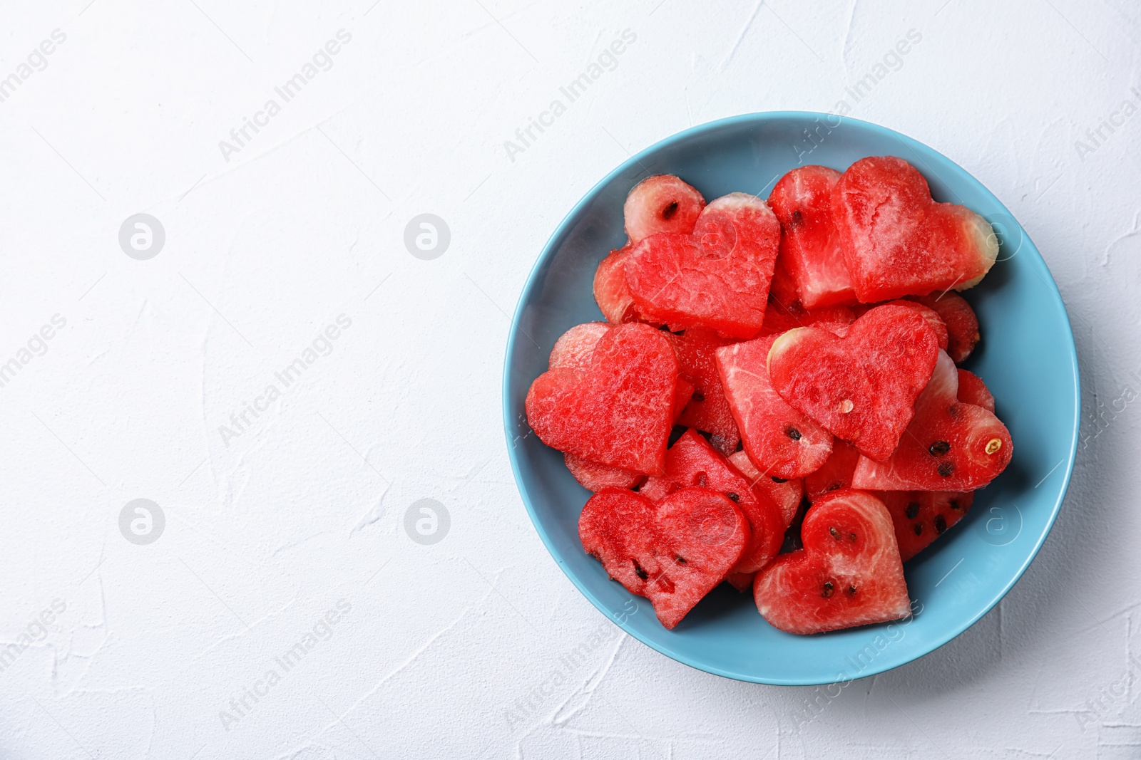 Photo of Plate with heart shaped watermelon slices on light background, top view