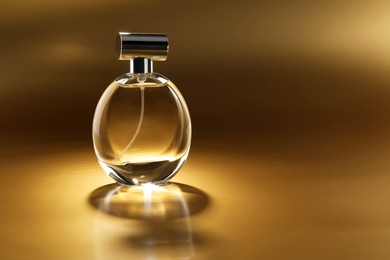 Photo of Luxury women's perfume. Sunlit glass bottle on golden background, space for text