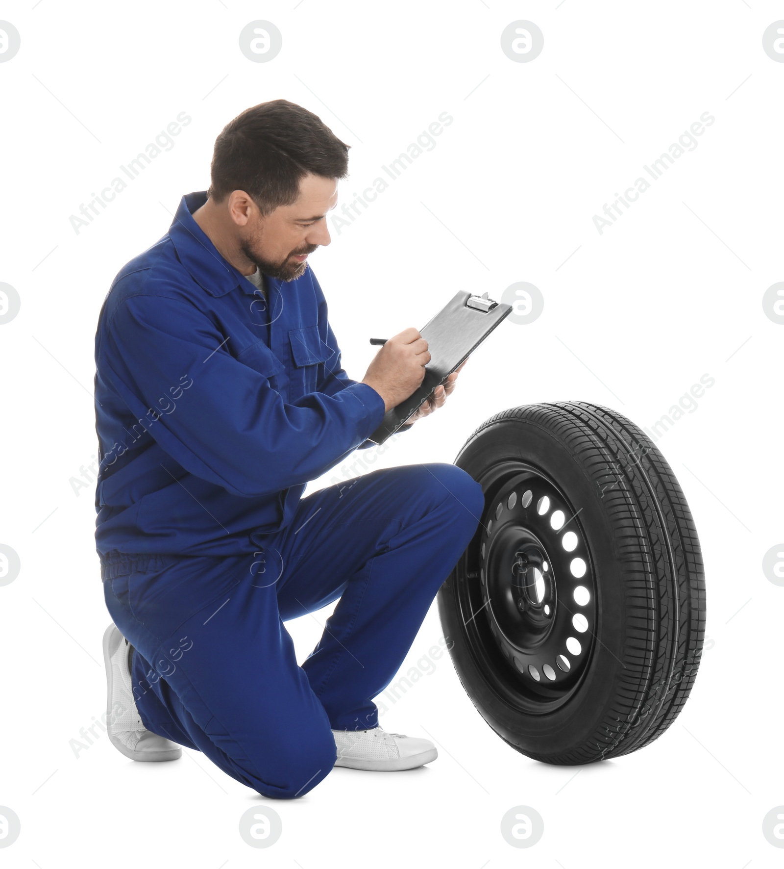 Photo of Professional auto mechanic with wheel and clipboard on white background