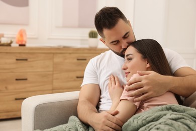 Photo of Affectionate young couple spending time together on sofa in living room. Space for text