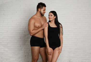 Photo of Young couple in black underwear near white brick wall