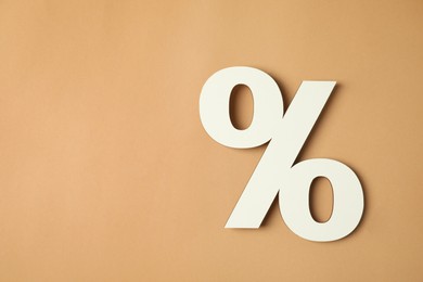 Photo of White percent sign on light brown background, top view. Space for text