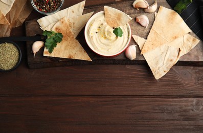 Photo of Flat lay composition with delicious hummus and pita chips on wooden table. Space for text