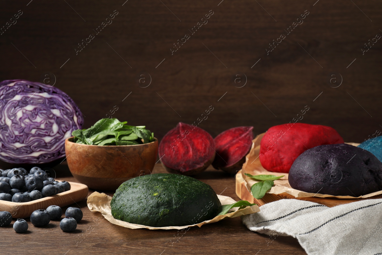 Photo of Dough painted with natural food colorings and ingredients on wooden table, space for text