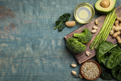 Different products rich in vitamin E on blue wooden table, flat lay. Space for text