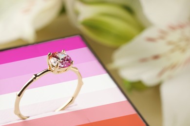 Image of Box in color of lesbian flag and beautiful engagement ring against blurred background, closeup
