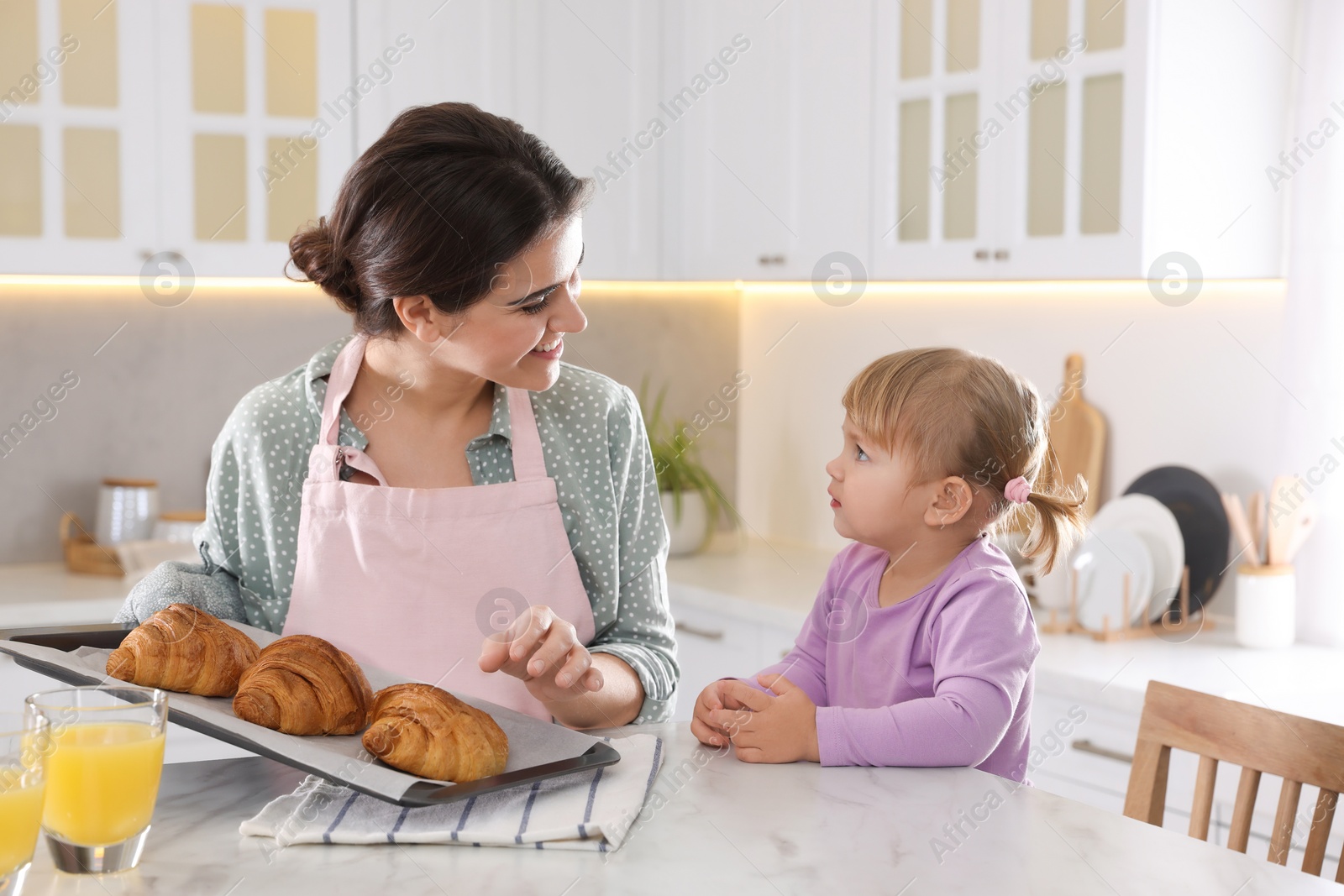 Photo of Mother and her little daughter having breakfast together in kitchen