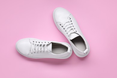 Photo of Pair of stylish white sneakers on pink background, top view