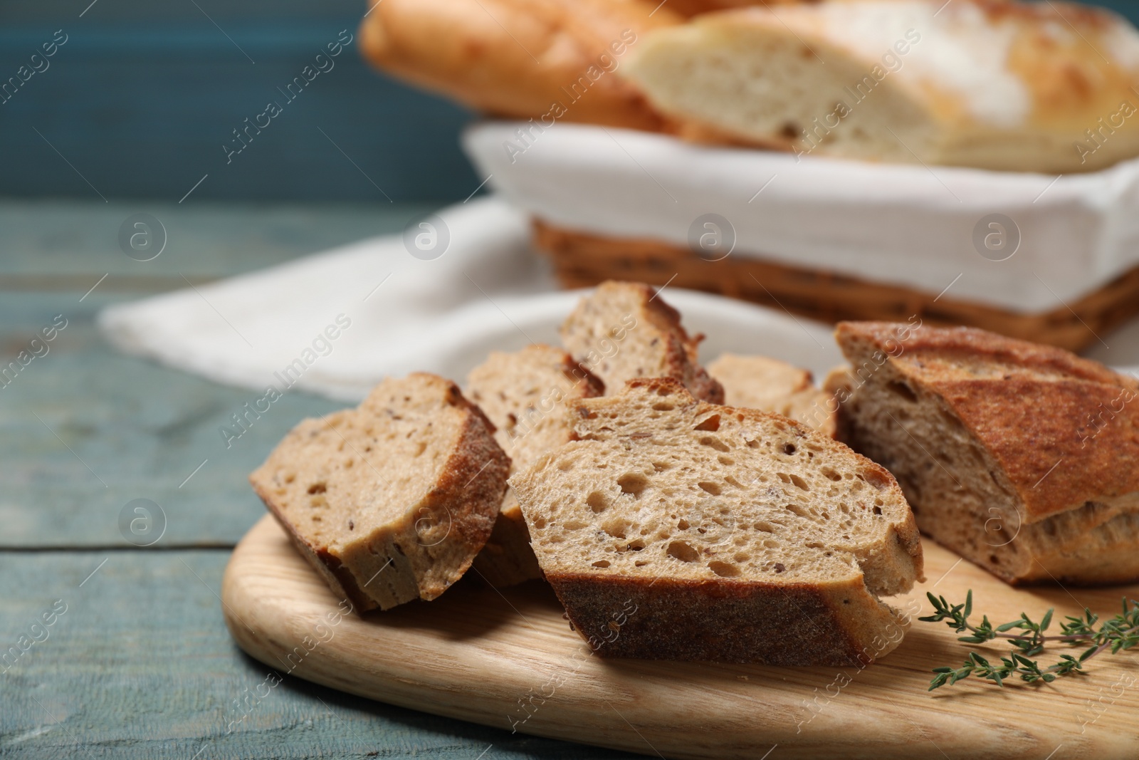 Photo of Cut buckwheat baguette with thyme on light blue wooden table, closeup