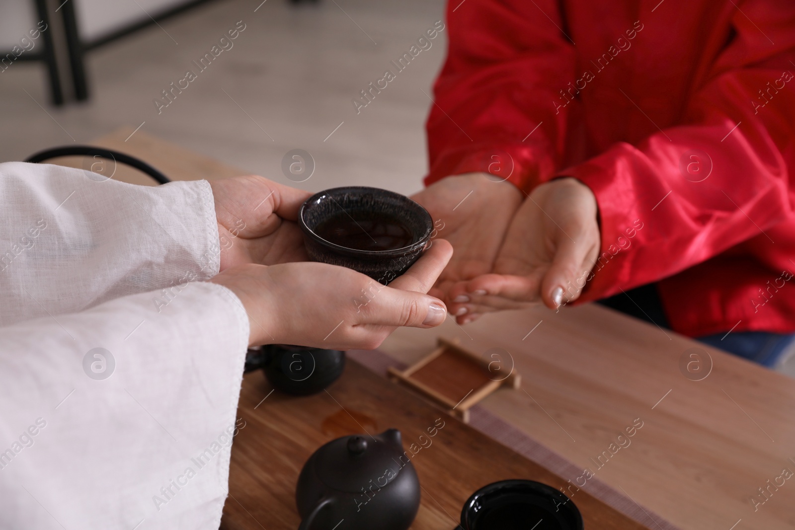 Photo of Master giving freshly brewed tea to guest during ceremony at table, closeup