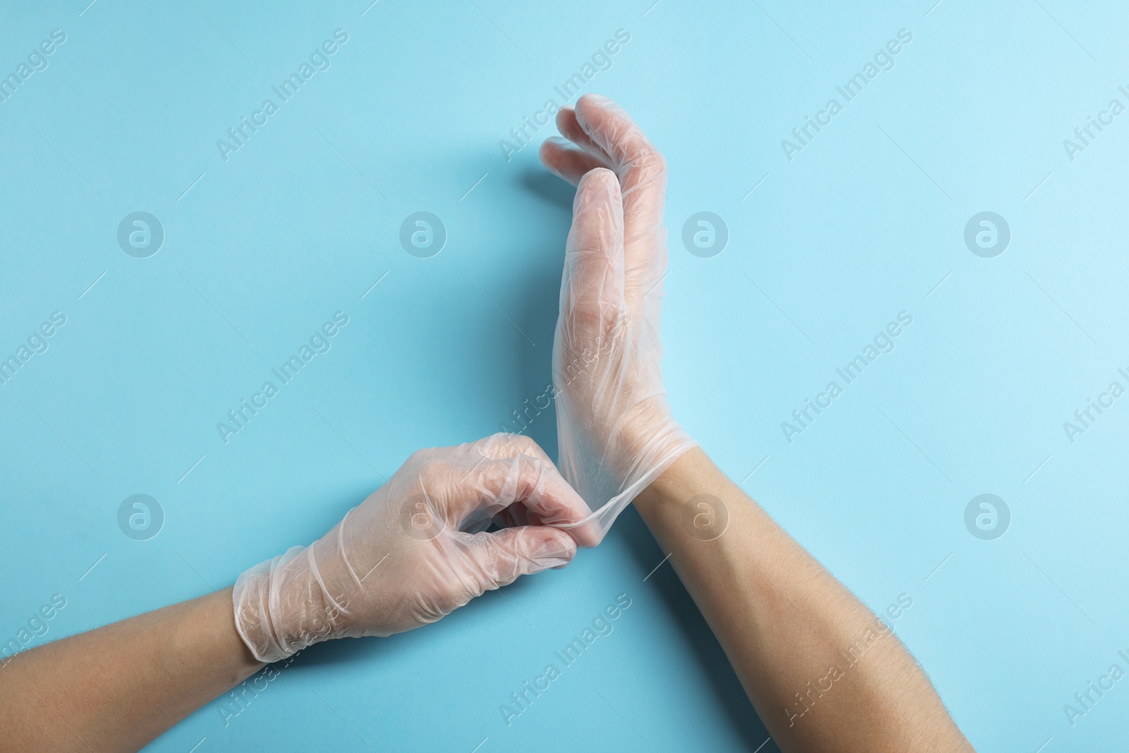 Photo of Doctor wearing medical gloves on light blue background, top view