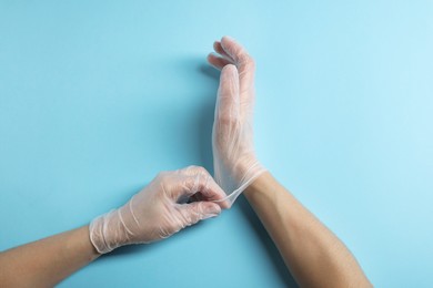 Photo of Doctor wearing medical gloves on light blue background, top view