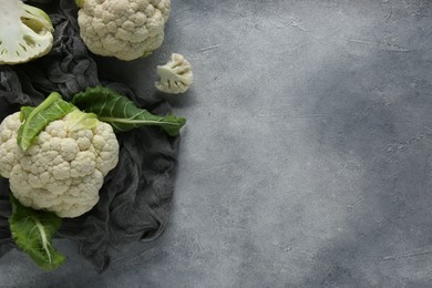Fresh whole and cut cauliflowers on grey textured background, top view. Space for text