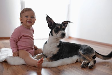 Adorable baby and cute dog on faux fur rug indoors