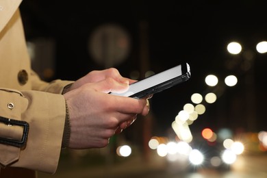 Photo of Man using smartphone on night city street, closeup