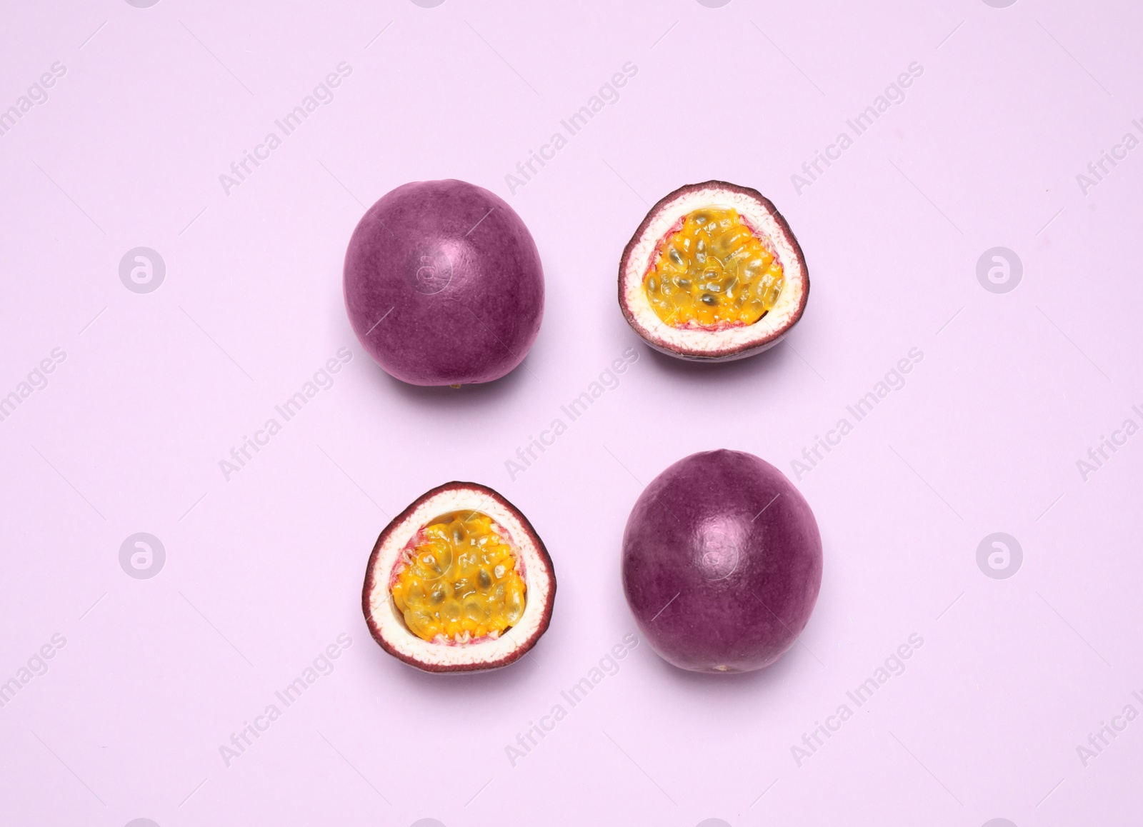 Photo of Fresh ripe passion fruits (maracuyas) on light violet background, flat lay