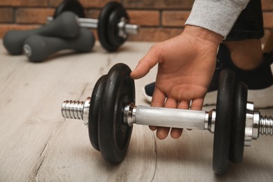 Athlete taking dumbbell indoors, closeup. Suffering from calluses on hand