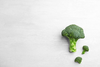 Photo of Fresh broccoli florets on light grey table, flat lay with space for text