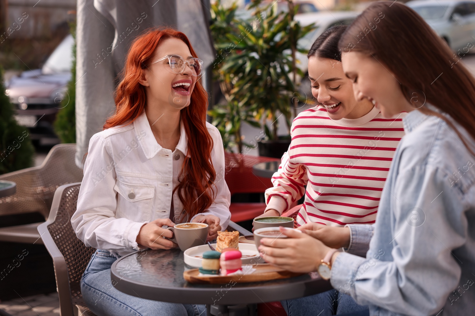 Photo of Happy friends talking and drinking coffee in outdoor cafe