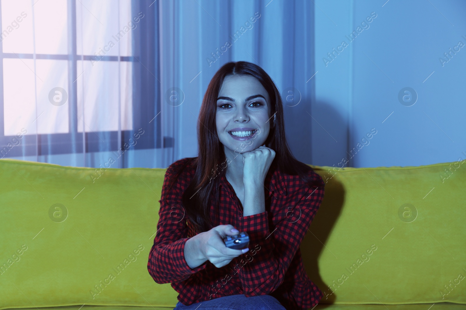 Photo of Beautiful young watching TV on sofa at home