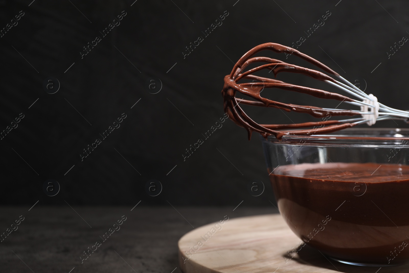 Photo of Bowl of chocolate cream and whisk on gray table, space for text