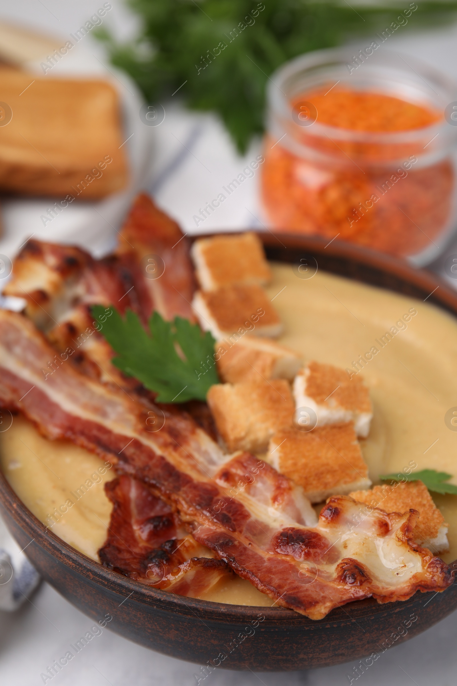 Photo of Delicious lentil soup with bacon and parsley in bowl on table, closeup