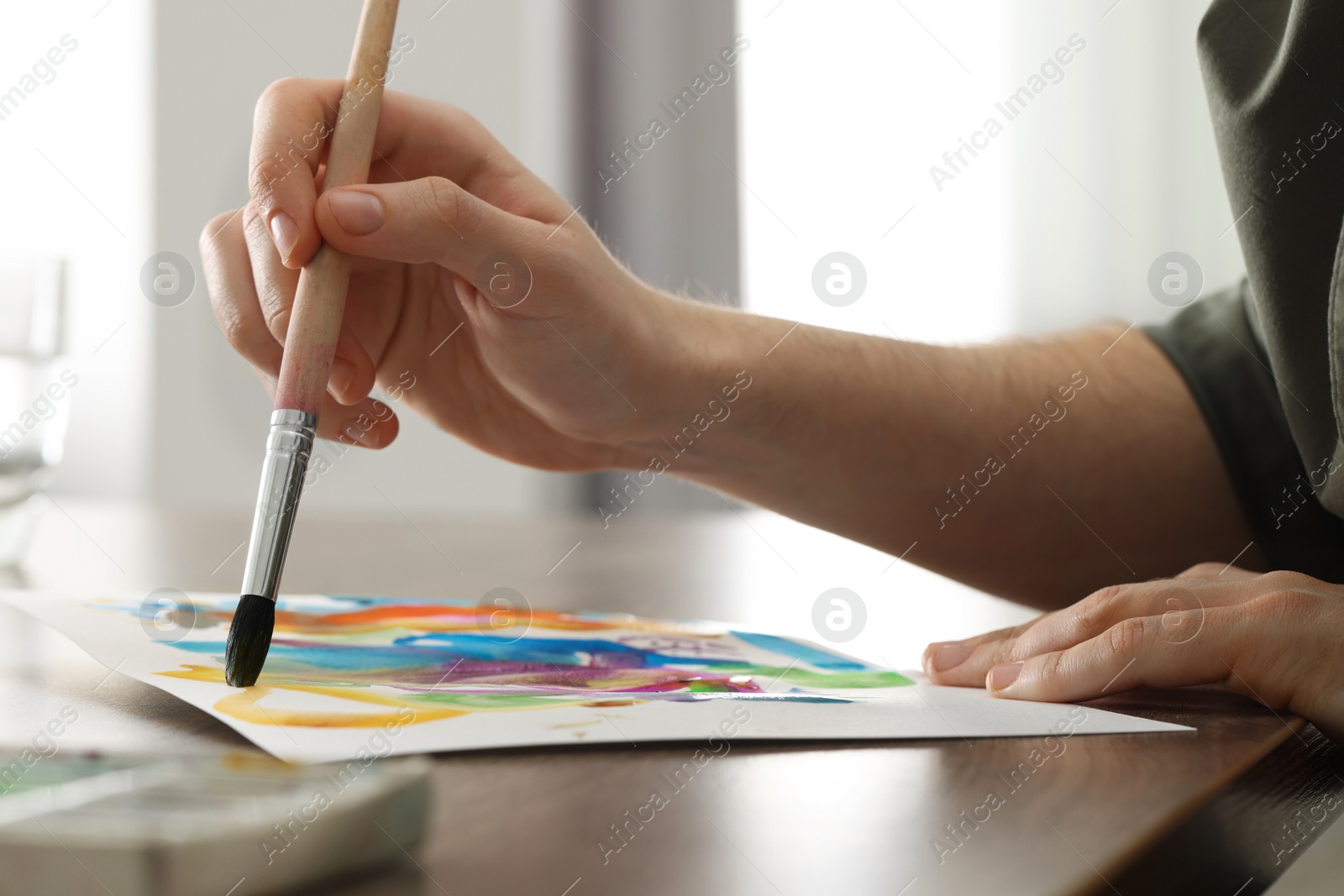 Photo of Woman painting with watercolor at wooden table indoors, closeup