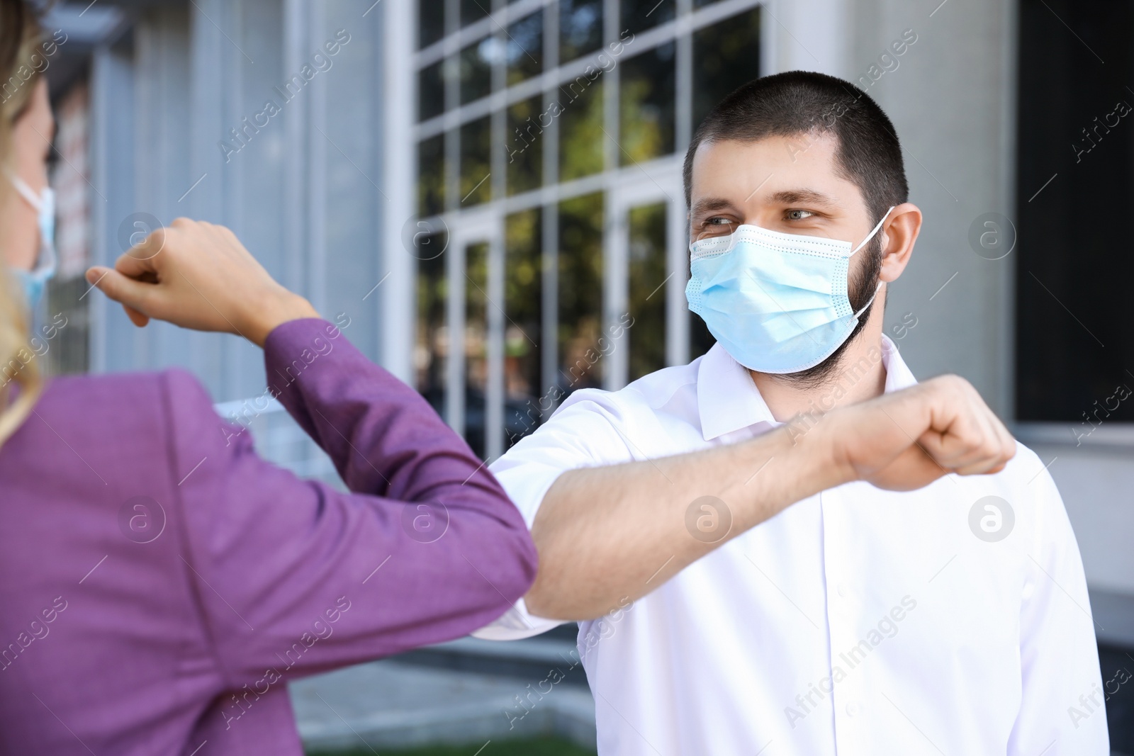 Photo of Man and woman bumping elbows to say hello outdoors. Keeping social distance during coronavirus pandemic