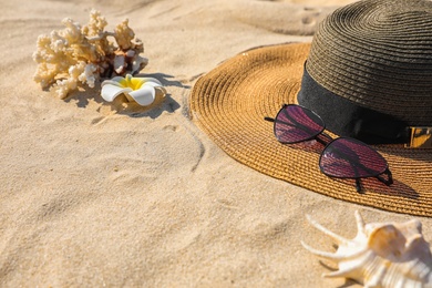 Photo of Stylish hat and sunglasses on sand, space for text. Beach accessories