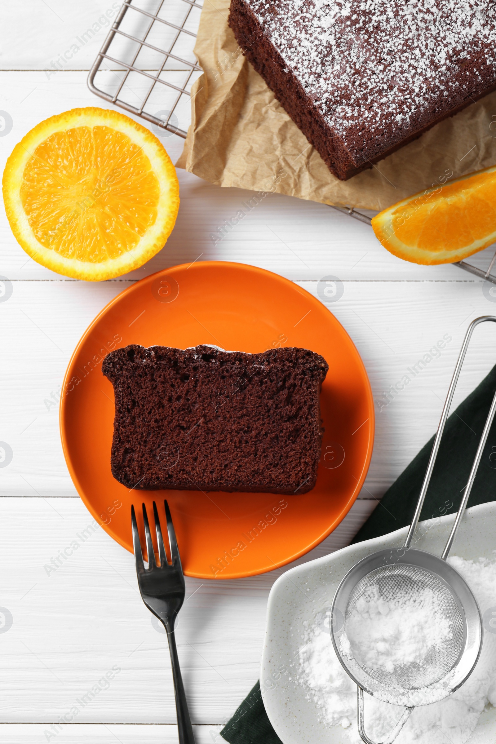 Photo of Tasty chocolate sponge cake and ingredients on white wooden table, flat lay