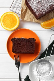 Photo of Tasty chocolate sponge cake and ingredients on white wooden table, flat lay