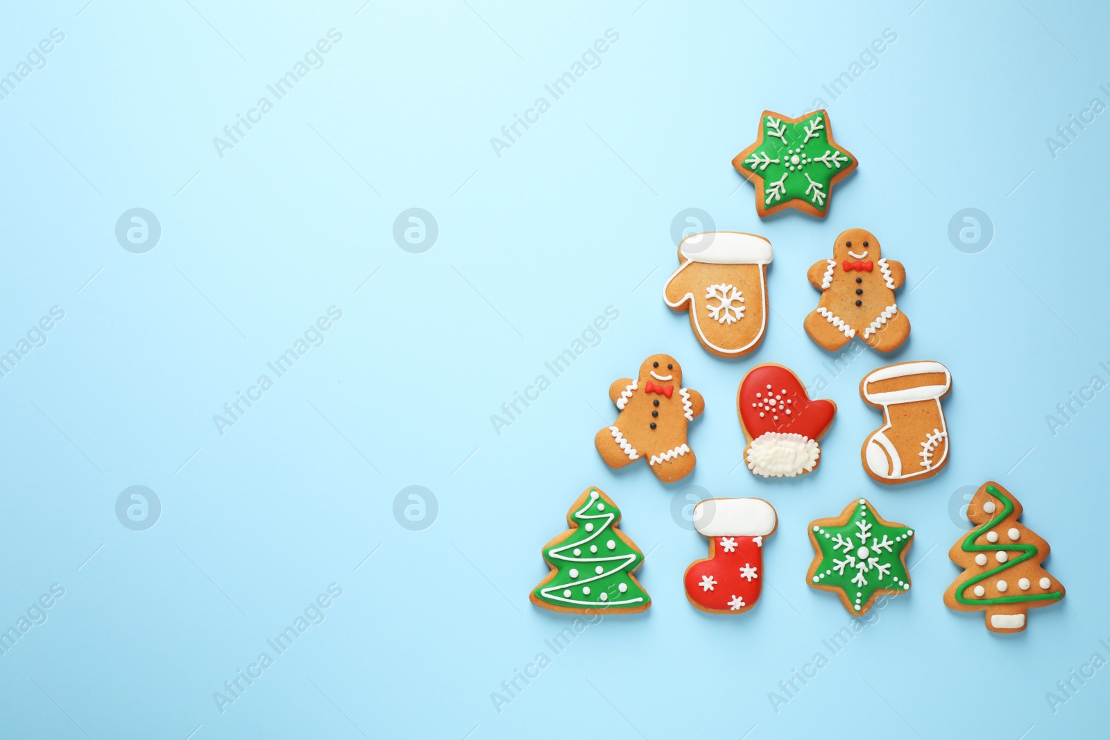 Photo of Christmas tree shape made of tasty homemade cookies on light blue background, flat lay. Space for text