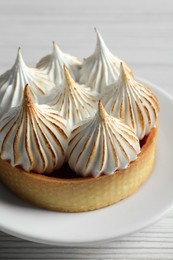 Photo of Tartlet with meringue on white wooden table, closeup. Tasty dessert