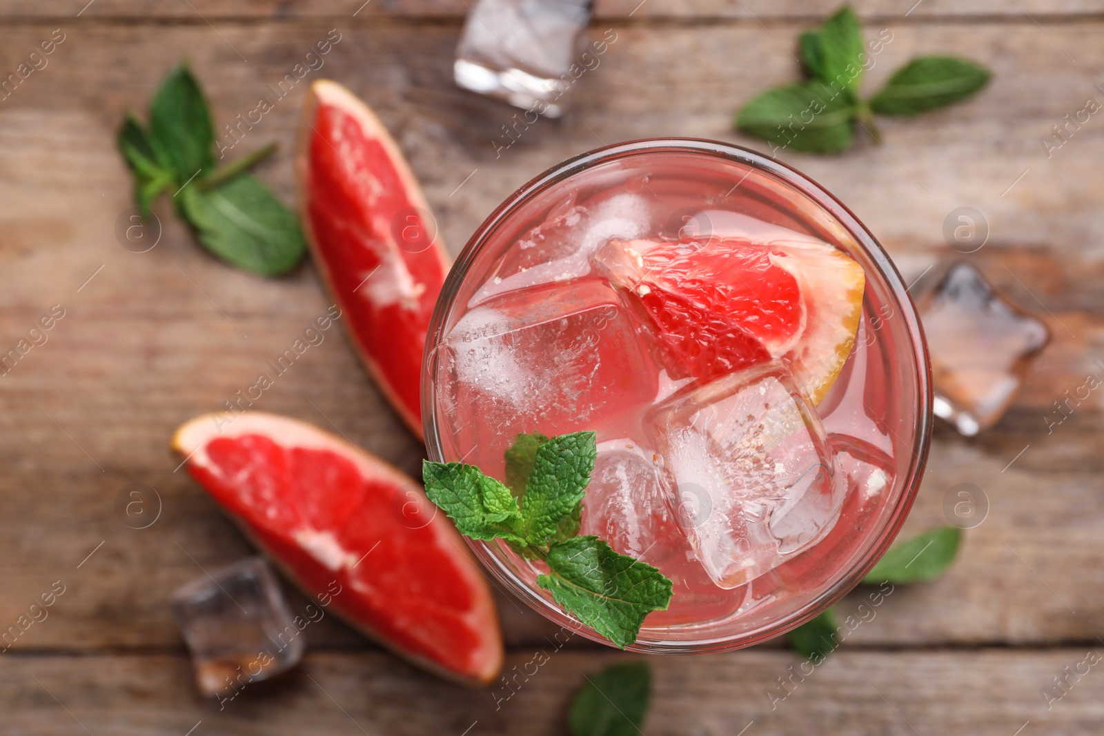 Photo of Glass of refreshing drink with grapefruit and mint on wooden table, top view