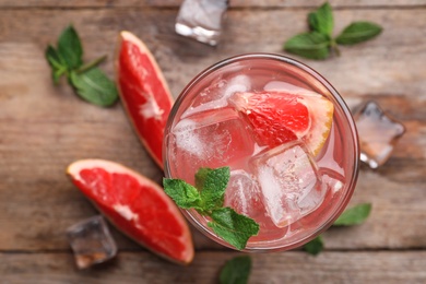 Photo of Glass of refreshing drink with grapefruit and mint on wooden table, top view