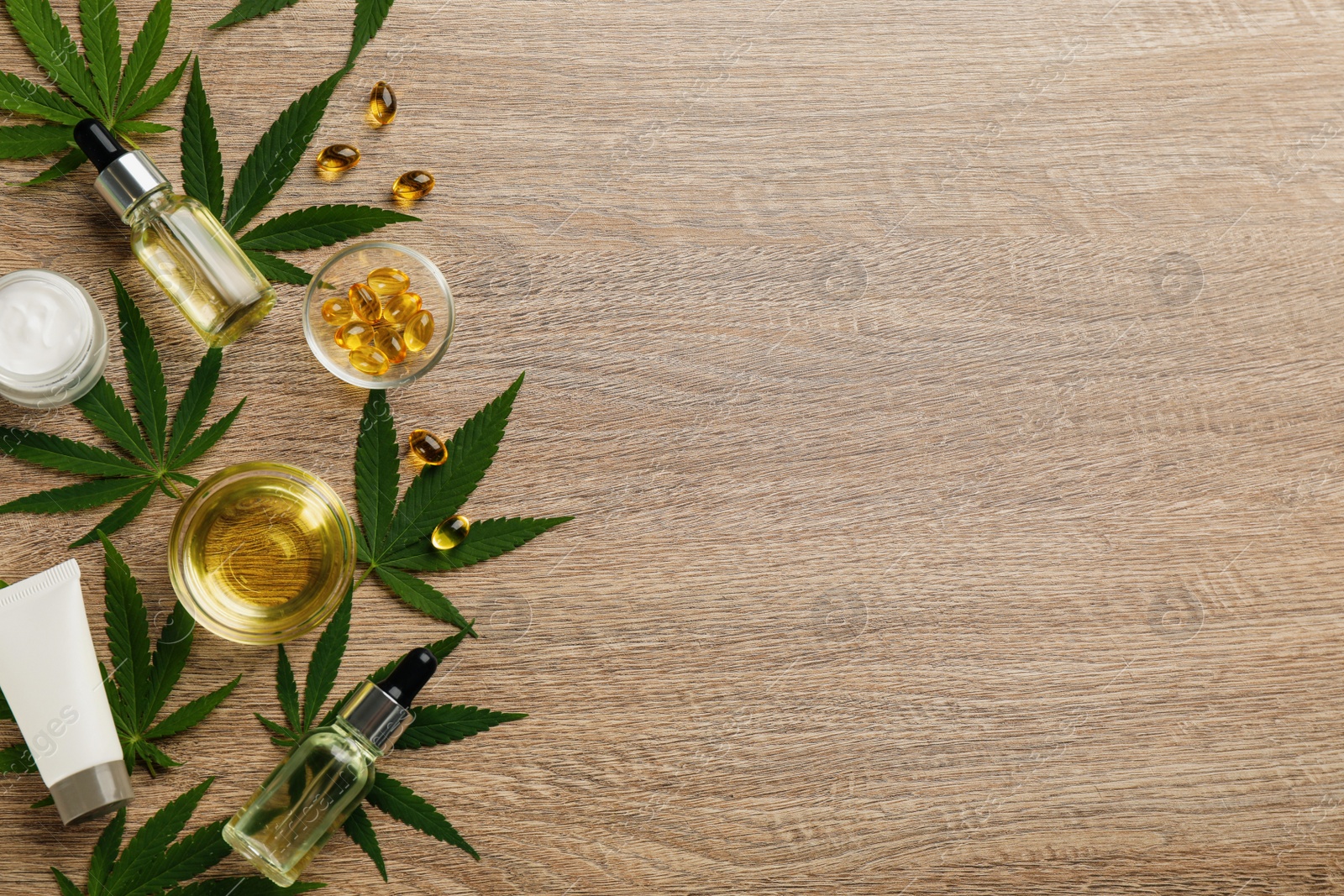 Photo of Flat lay composition with hemp leaves, CBD oil and THC tincture on wooden table, space for text