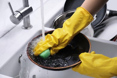 Photo of Woman washing frying pan with sponge in kitchen sink, closeup